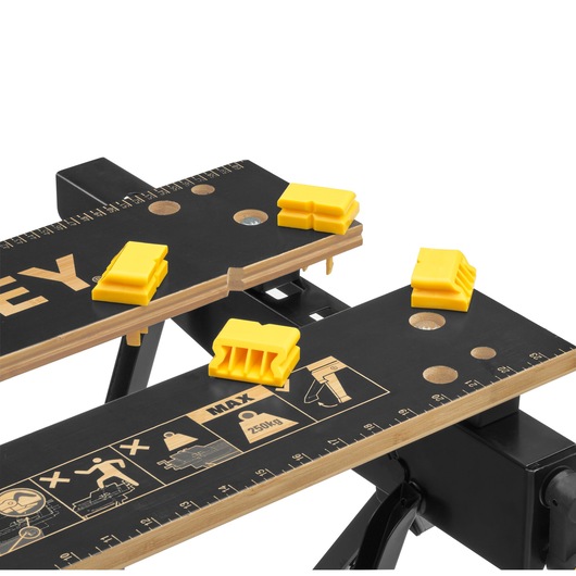 STANLEY STST83400-1 workbench top view with yellow clamps, rulers, and safety icons on black surface.