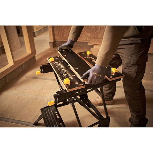 Photo of STANLEY STST83400-1 workbench in use in a workshop, black and yellow portable work table.