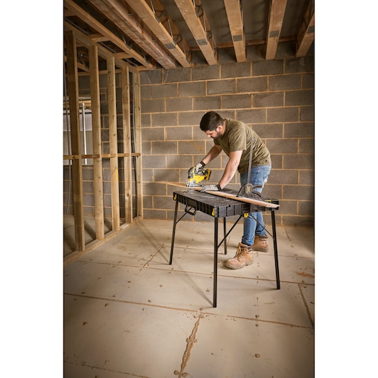 STANLEY STST83492-1 folding work table in use during construction, black tabletop, sturdy legs.