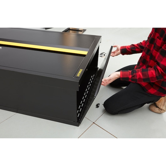 Photo of STANLEY STST97957-1 black metal storage cabinet with open front panel during assembly, workshop setting.